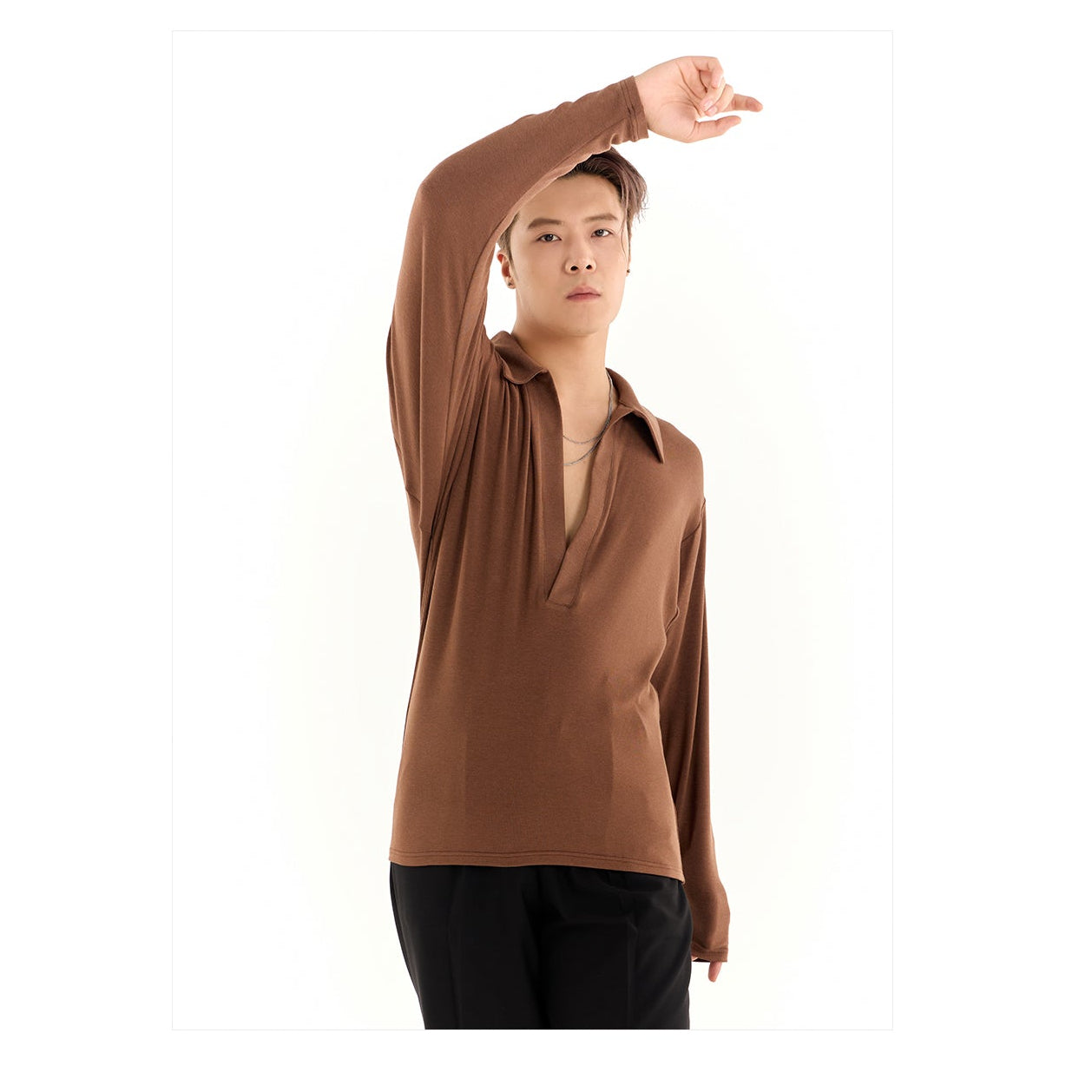 Person wearing a brown long-sleeve shirt with a brand logo above