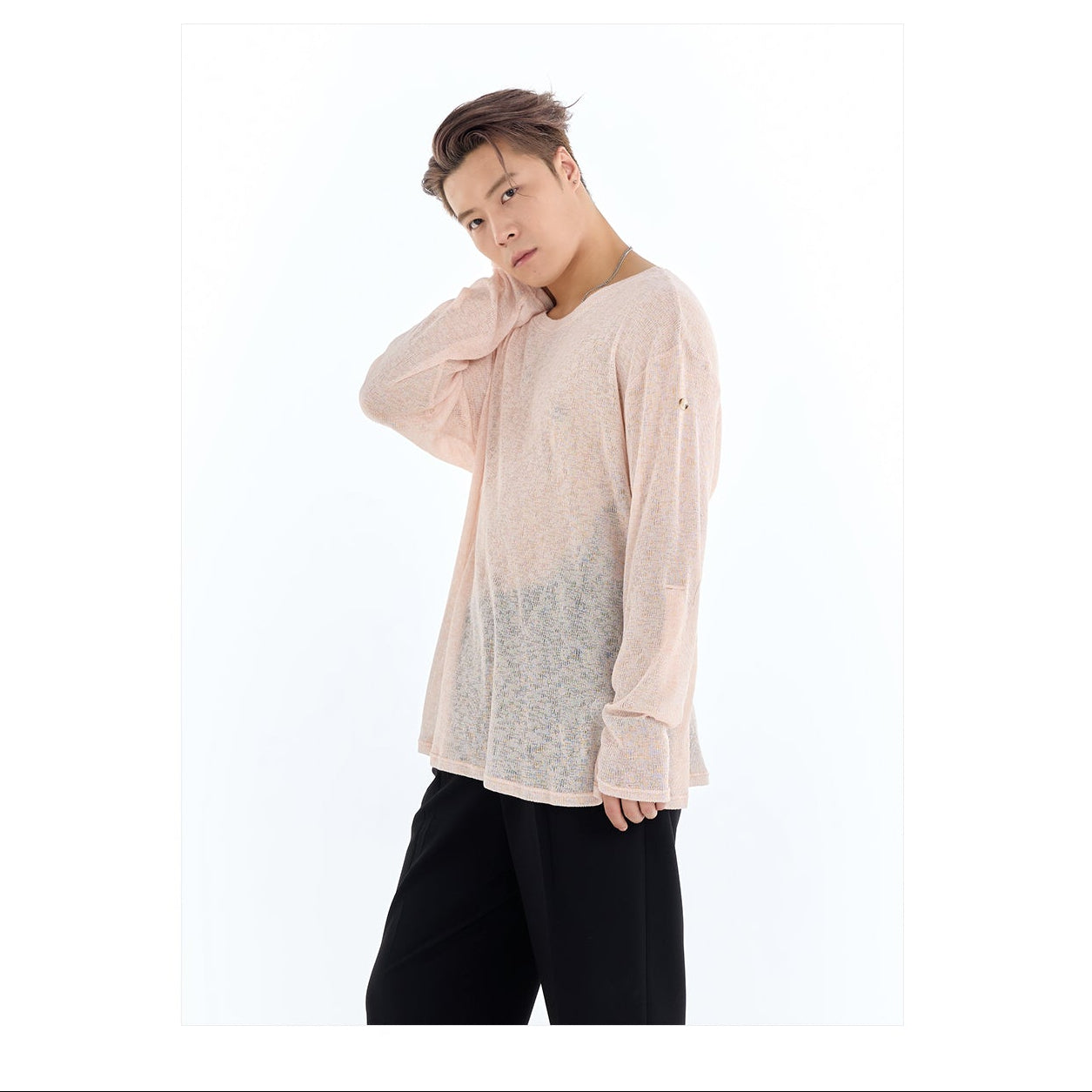 Person wearing a light pink shirt with a brand logo in the corner