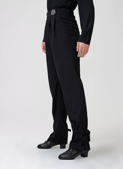 A model wearing a black long-sleeve dance top and matching high-waisted black pants with a silver buckle belt, black dance shoes, and a BOBO DANCE logo on the sleeve and upper left.