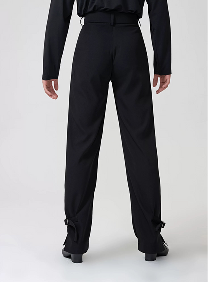A model from the back wearing black BOBO DANCE dancewear, featuring a long-sleeve top and high-waisted, wide-leg pants with ankle straps, set against a plain light gray studio background.