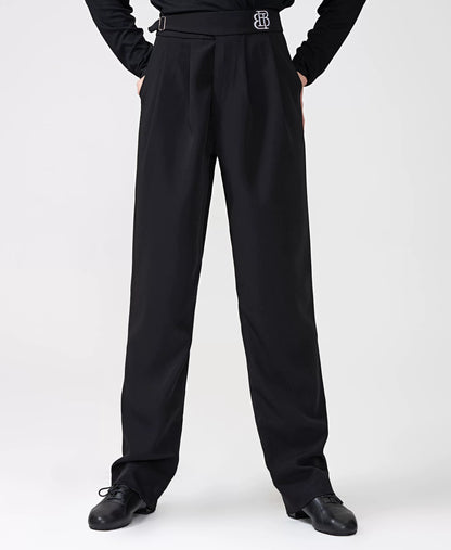 A model wearing a black long-sleeve top and matching high-waisted black trousers with a decorative silver 'BB' logo belt buckle, standing against a light gray studio background. The BOBO DANCE brand logo is visible in the top left corner.